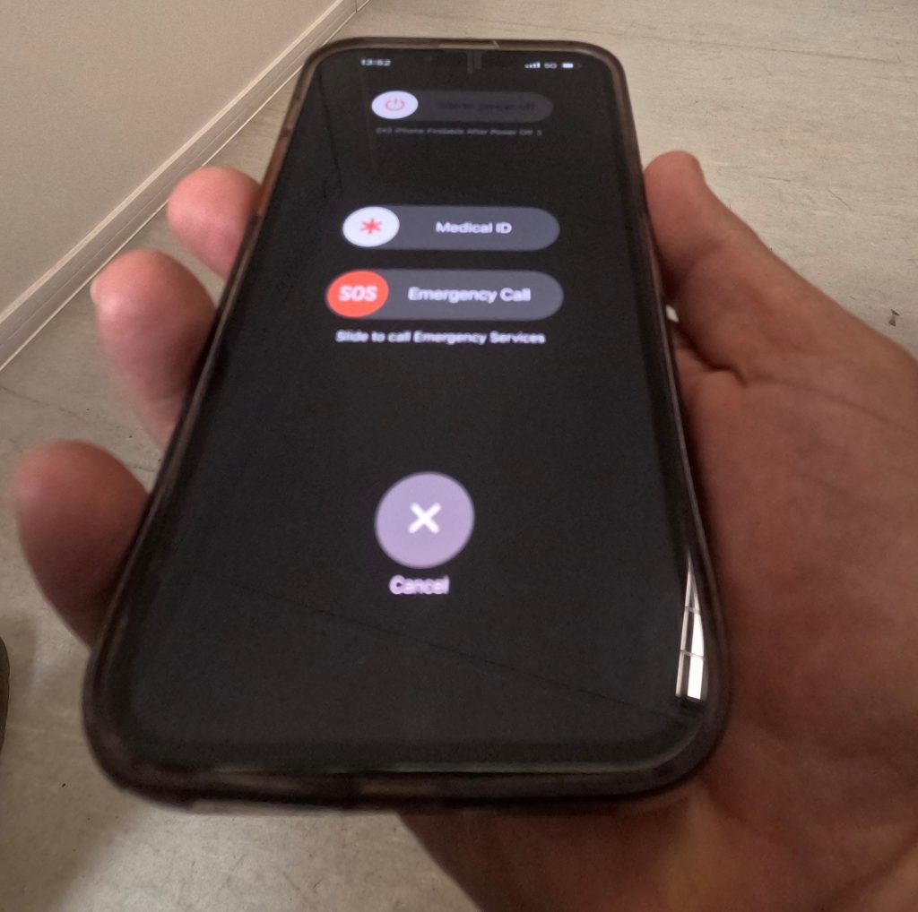 someone holding an iphone having pressed the power off and volume down button and the options shown: Slide to power off, Midical ID, SOS Emergency Call